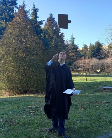 Veliko in graduation robes throwing his cap in the air 